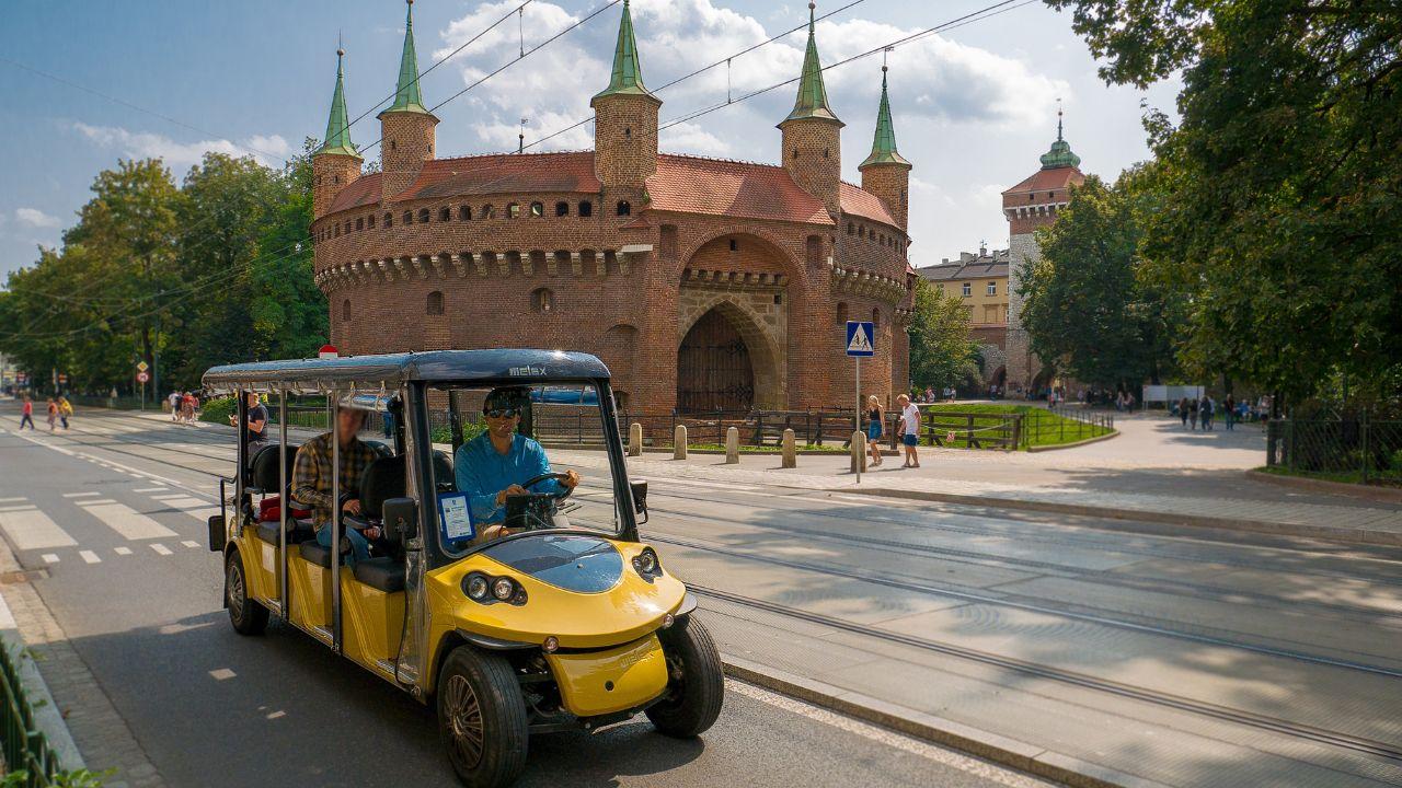 Turister som njuter av en tur runt Krakow i en miljövänlig melex.
